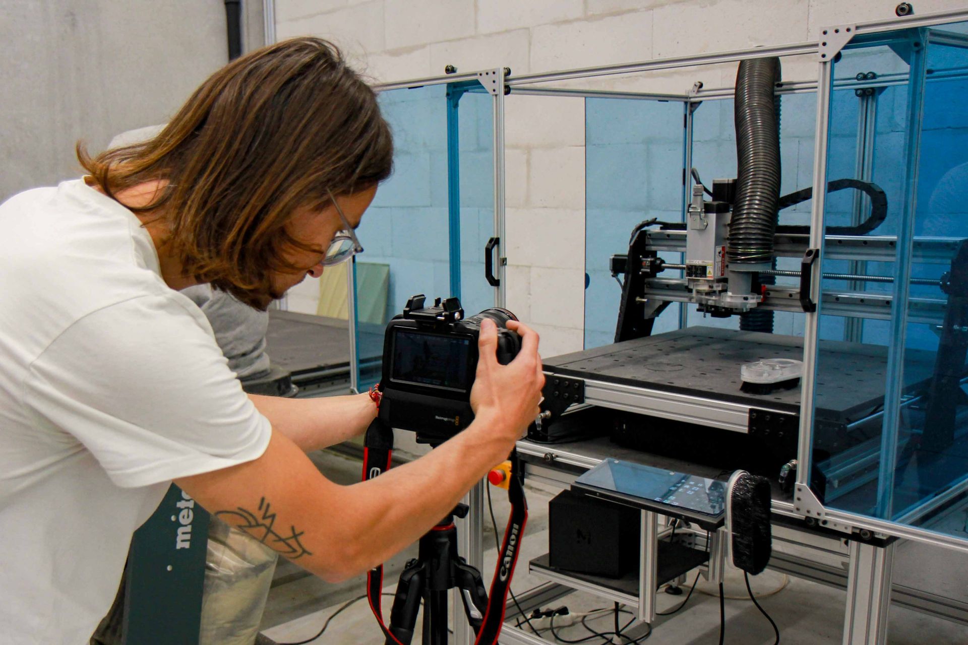 Person setting up a camera pointed towards a CNC machine