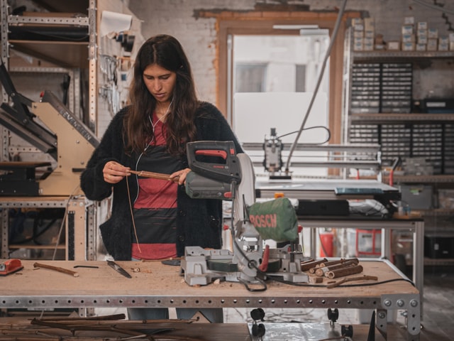 Fablab member working on a mitter saw in a workshop with a Mekanika CNC milling machine in the background