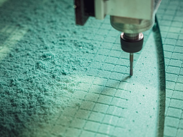 Closeup of a cnc milling machine's end mill milling in green expanded foam