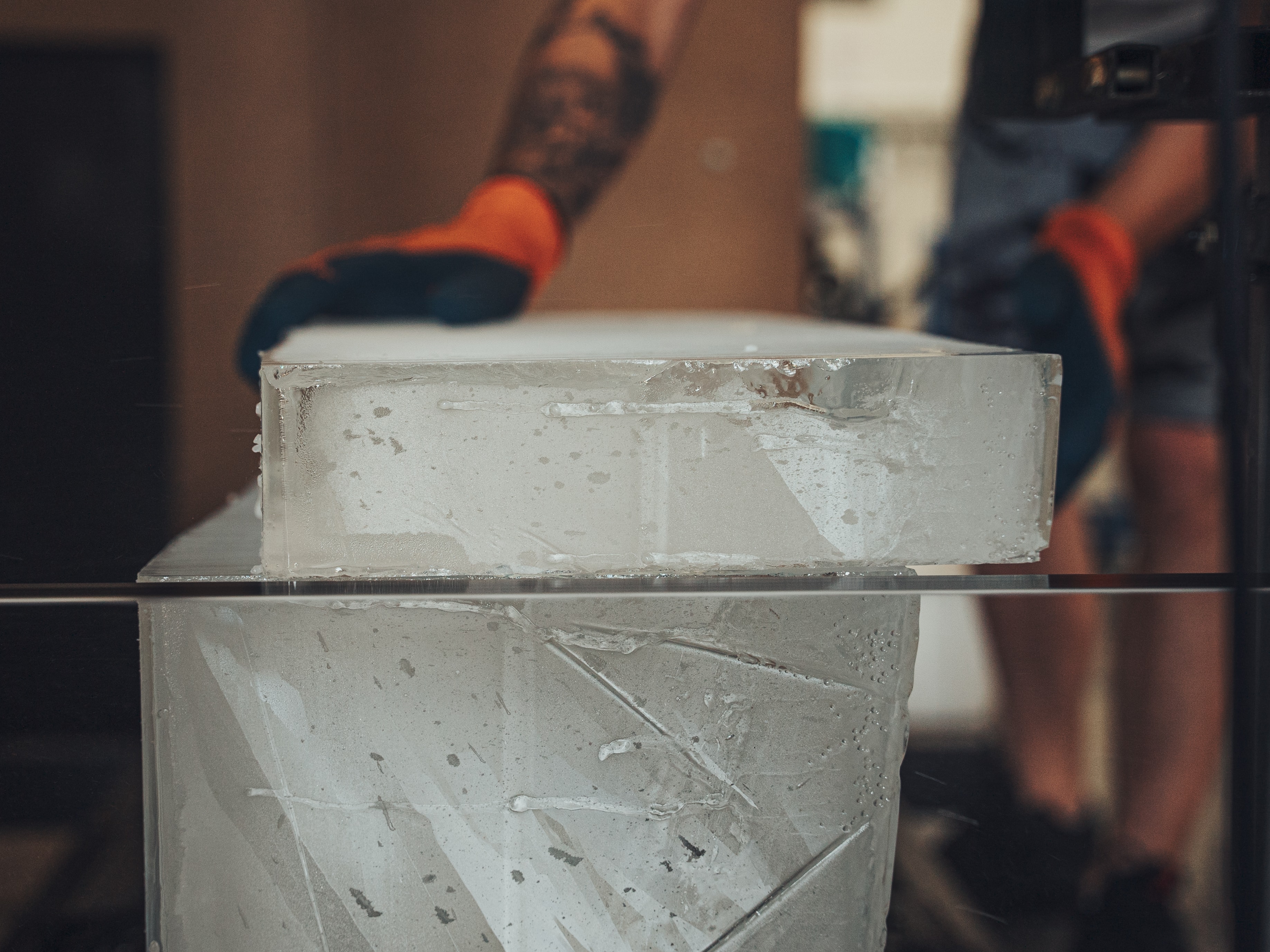 big ice block being sliced in slabs with hands of the operator