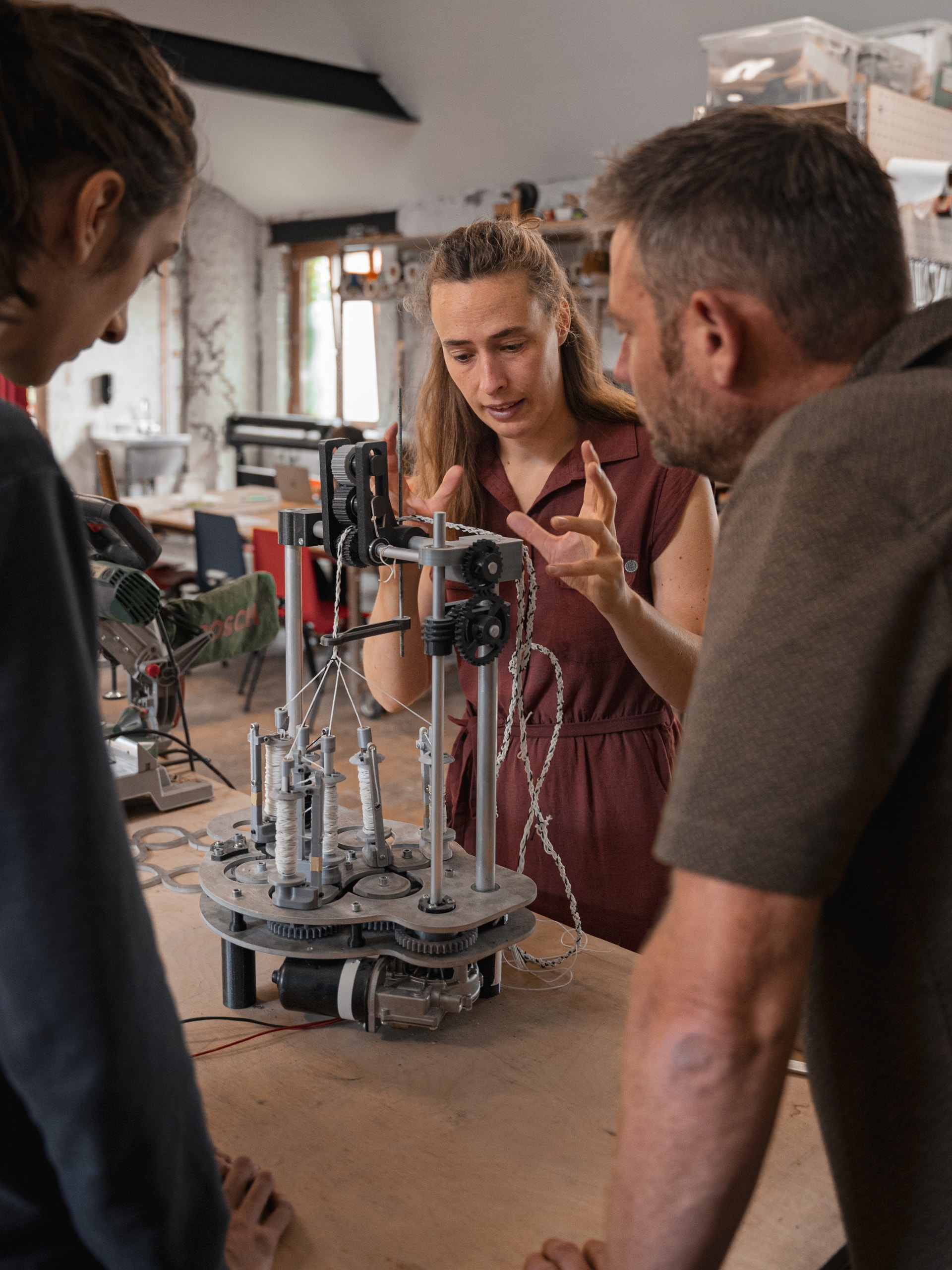 Close up picture of people observing a custom made DIY weaving machine in a fab lab