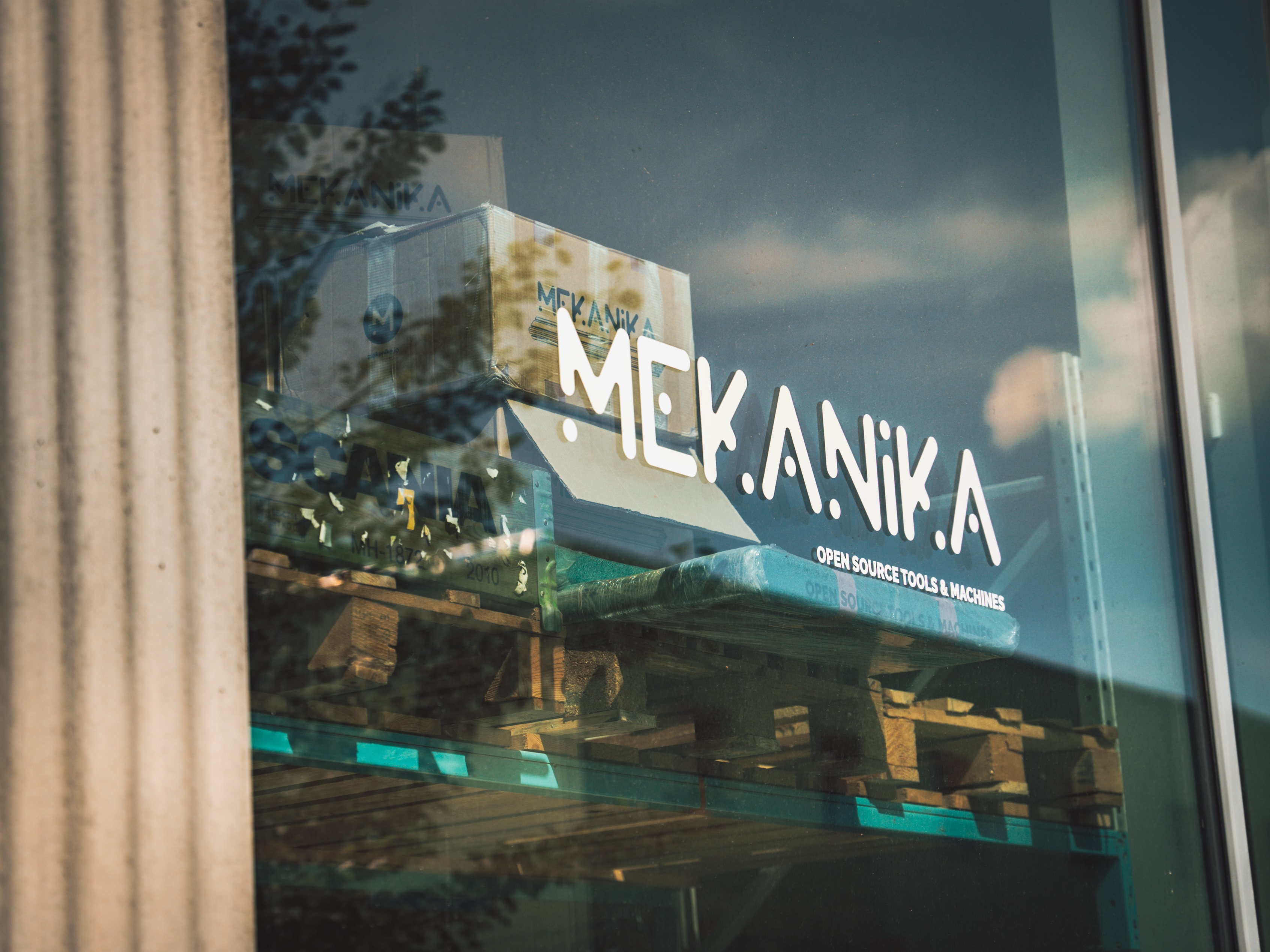 The mekanika logo on the window with a sunny reflection